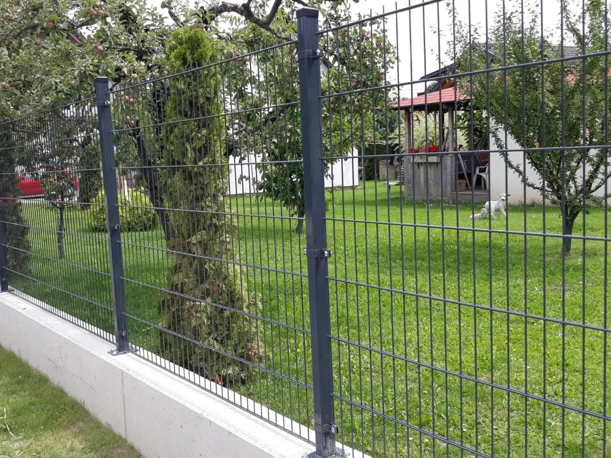 2D táblás kerítés antracit kivitelben, folyamatos beton lábazaton, kertes ingatlanon